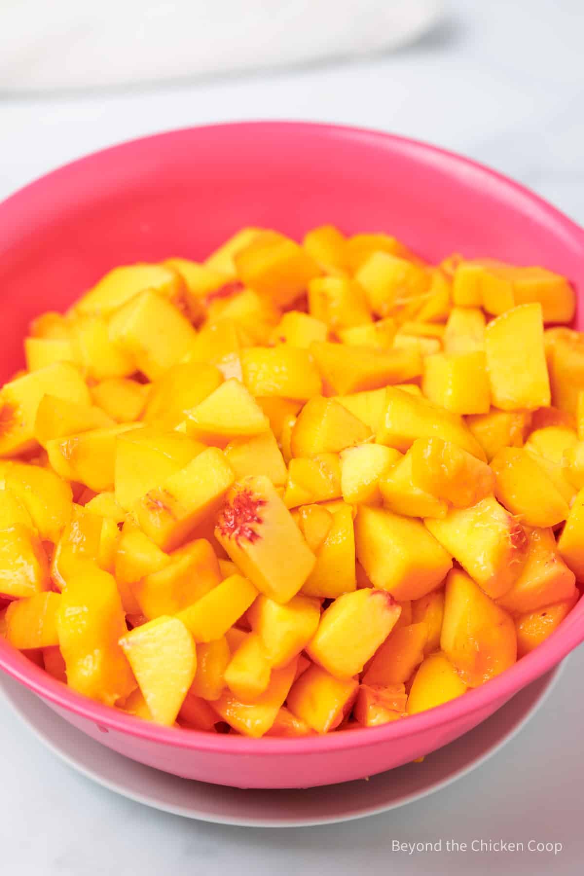 Chopped peaches in a pink collander.