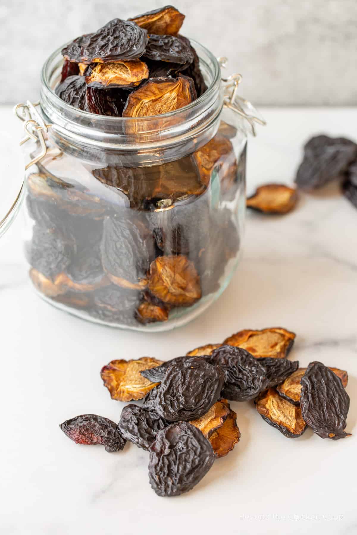 Dried prunes in a pile and in a jar. 