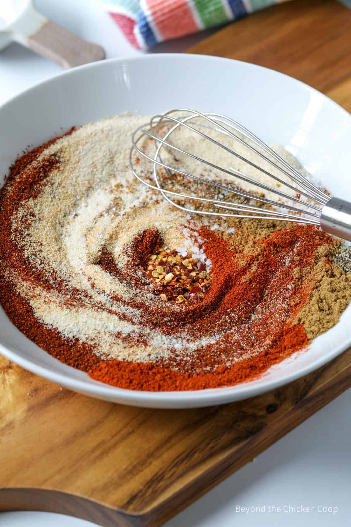 Spices in a bowl with a whisk.