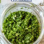 A closeup shot of freshly made Italian gremolata in a glass jar.