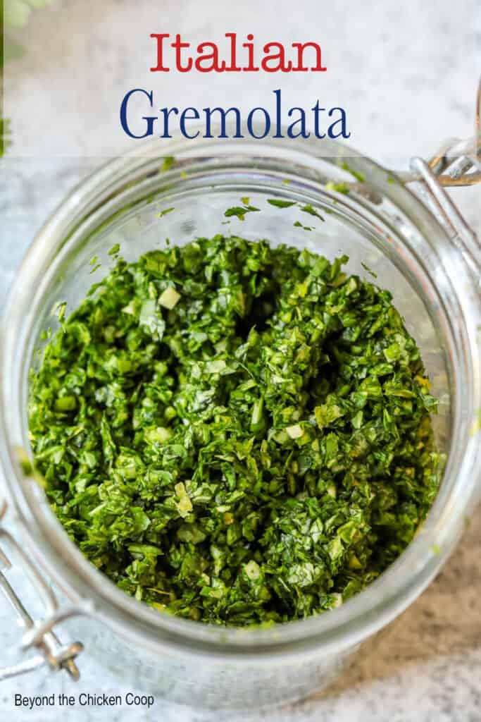 A closeup shot of freshly made Italian gremolata in a glass jar.