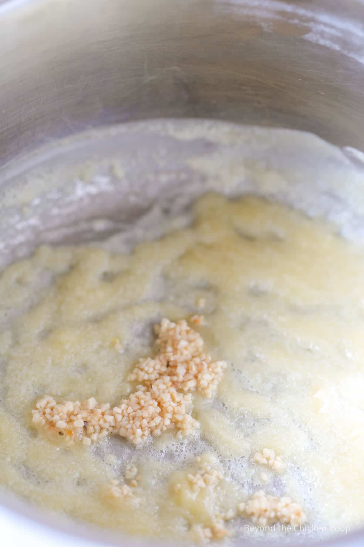 A roux in a saucepan with chopped garlic.