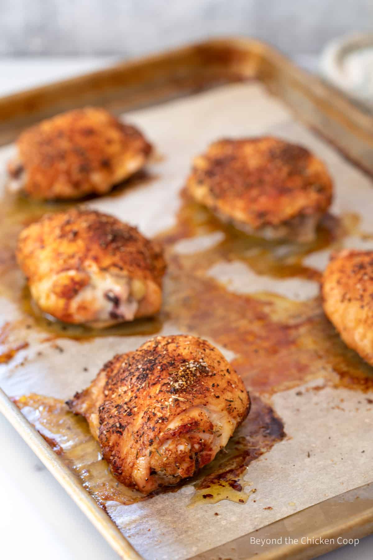 Cooked chicken thighs on a baking sheet.