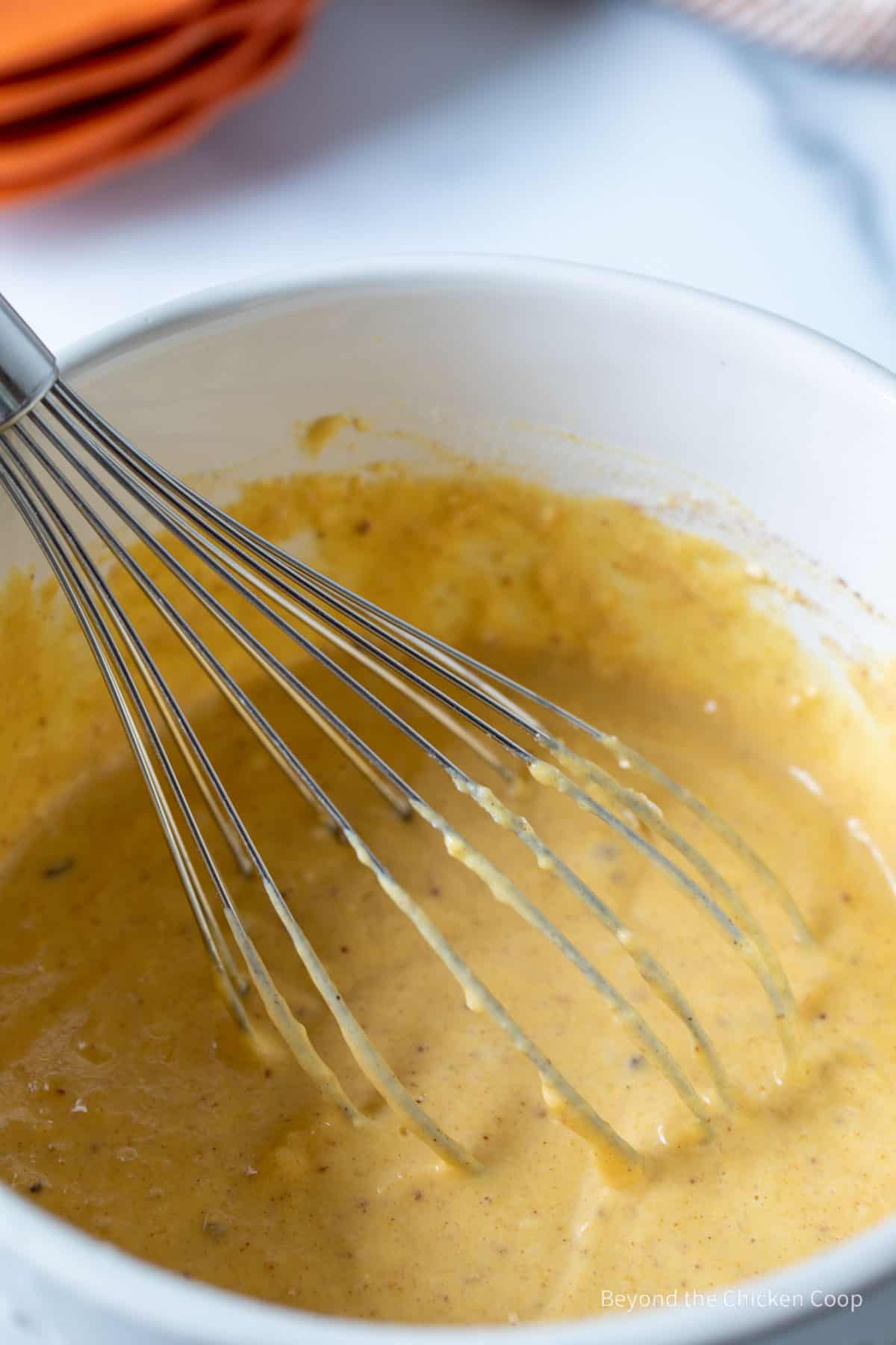 Waffle batter in a bowl with a whisk.