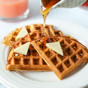 A plate of waffles topped with butter and syrup.