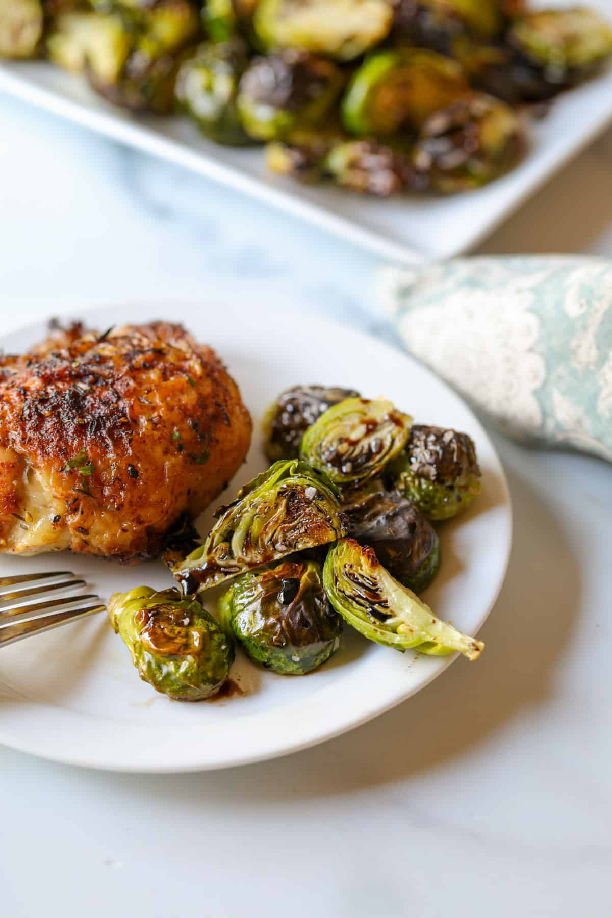 Roasted brussels sprouts on a plate with chicken. 