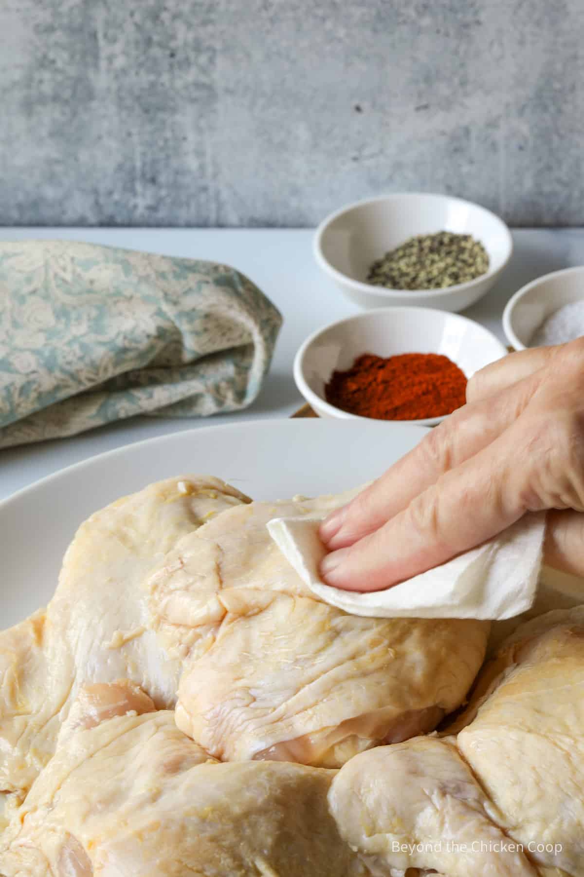 Drying chicken thighs with a paper towel.