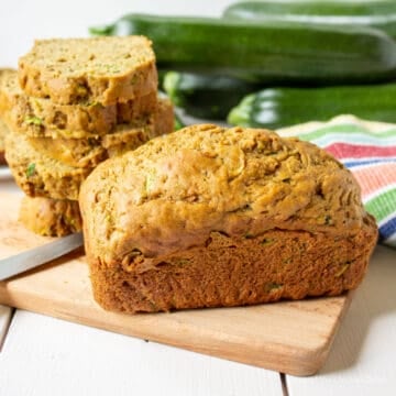 Mini loaf of zucchini bread on a wooden cutting board.