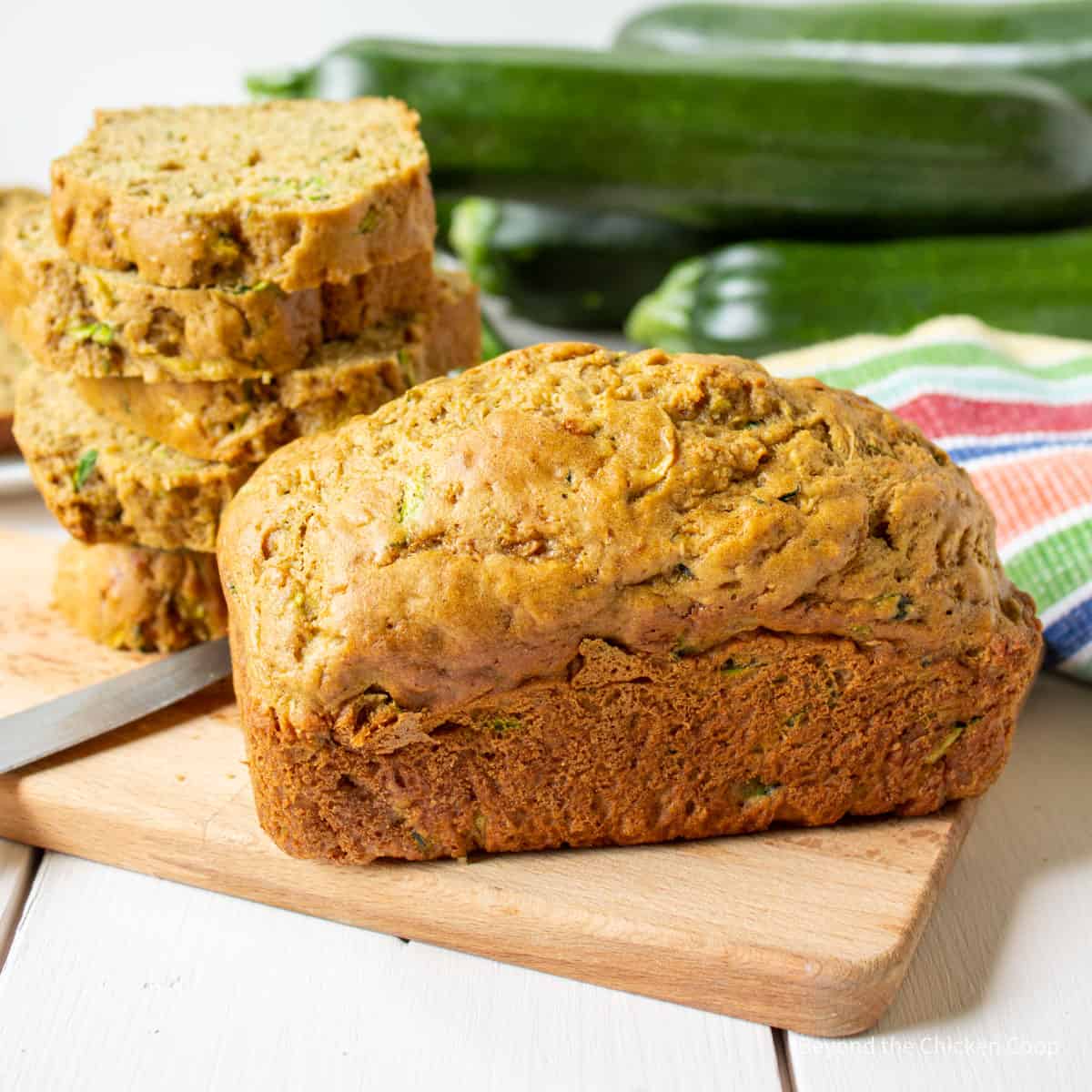 Mini loaf of zucchini bread on a wooden cutting board.