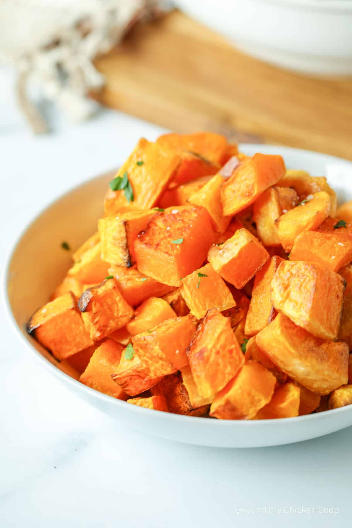 Cubed squash in a bowl with a bit of parsley.
