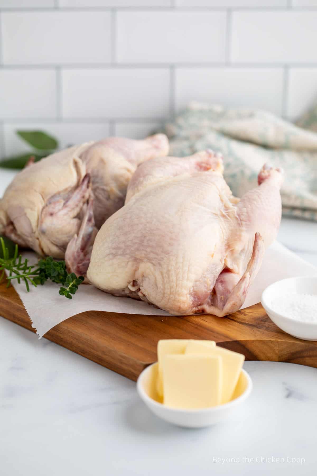 Two cornish hens on a cutting board. 