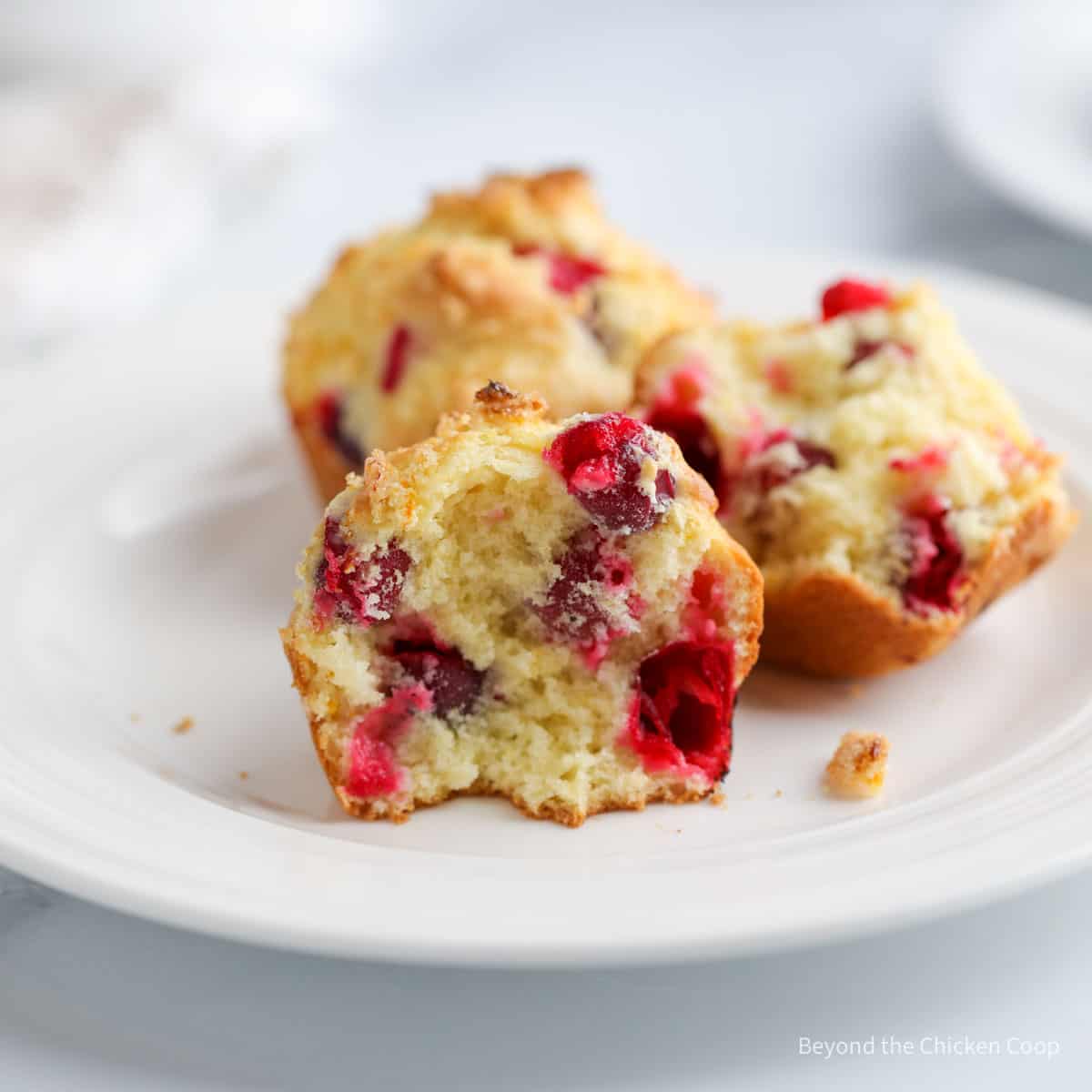 A half of a muffin filled with cranberries on a plate.