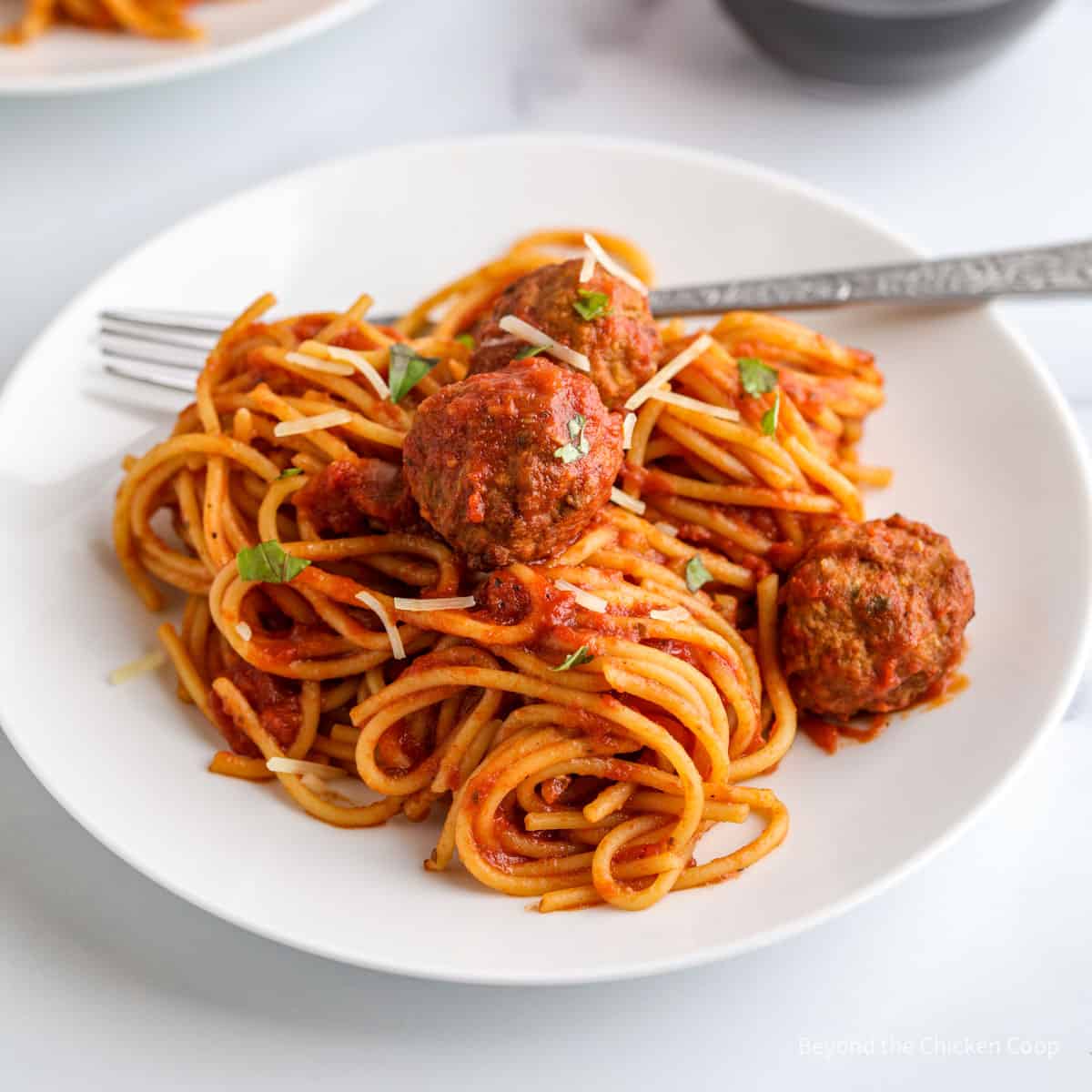 Spaghetti with sauce and meatballs on a white plate.