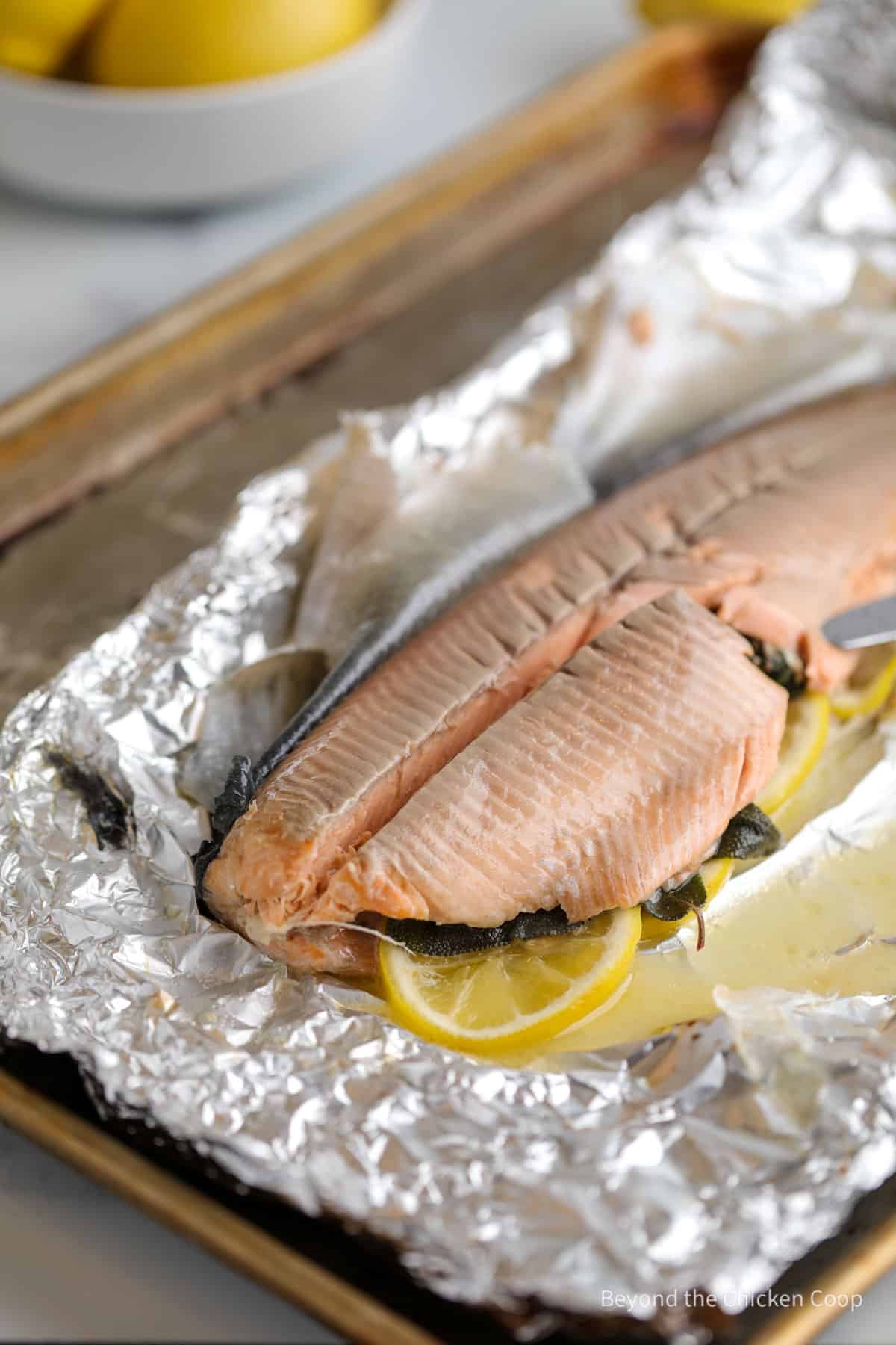 Slicing a whole baked trout. 