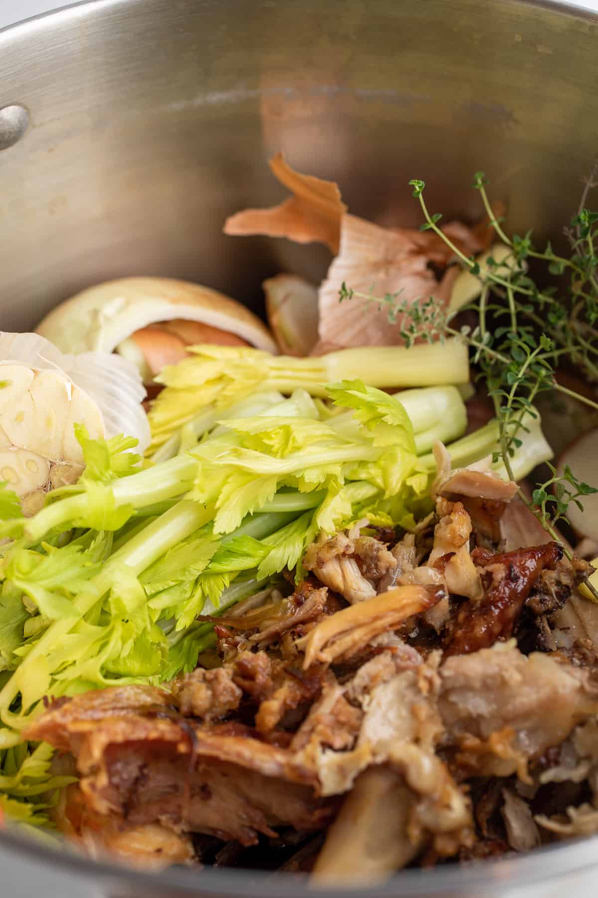 A stockpot filled with turkey bones, celery and onions. 