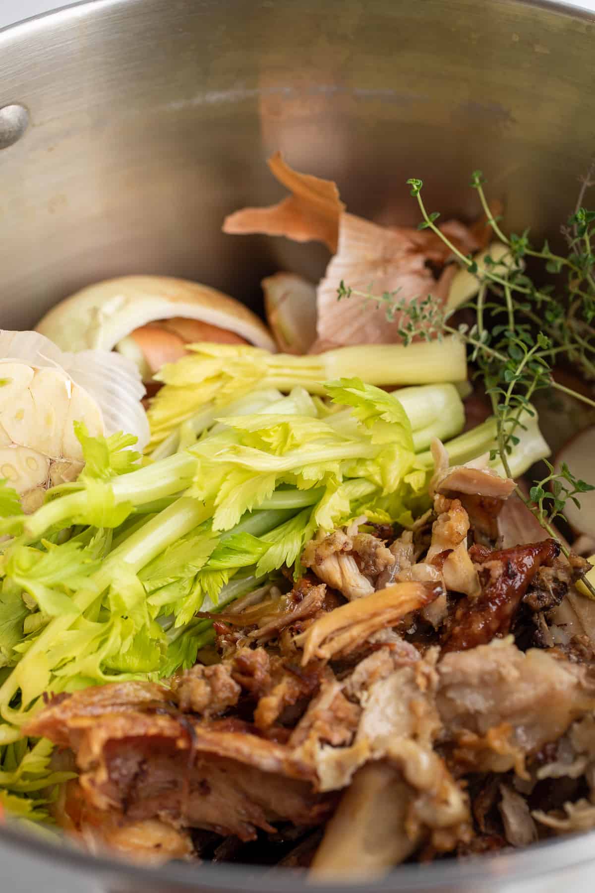 A stockpot filled with turkey bones, celery and onions.