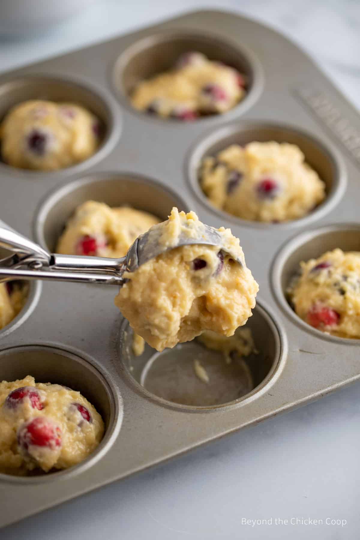Scooping muffin batter into a tin.