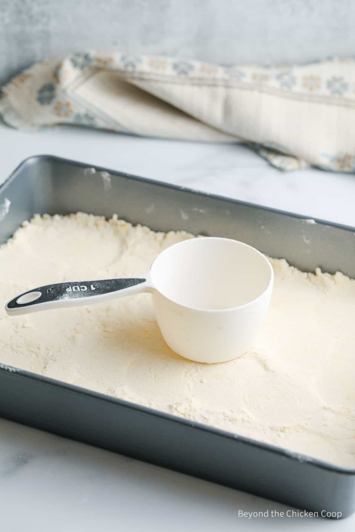 Pressing down a crust with a measuring cup.