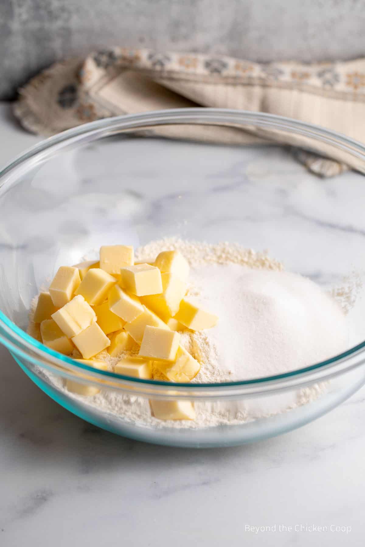 Cubes of butter in a mixing bowl with flour and sugar.
