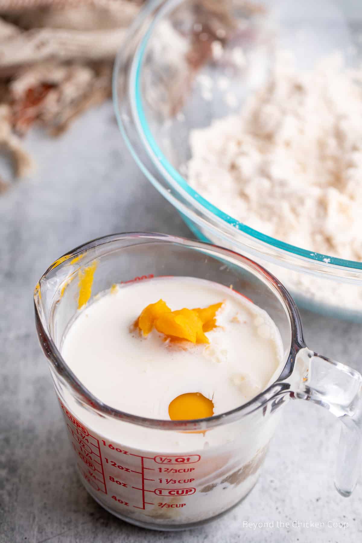 A large measuring cup with cream, pumpkin and eggs.