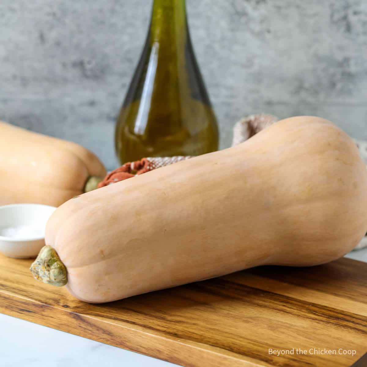 A whole butternut squash on a cutting board.