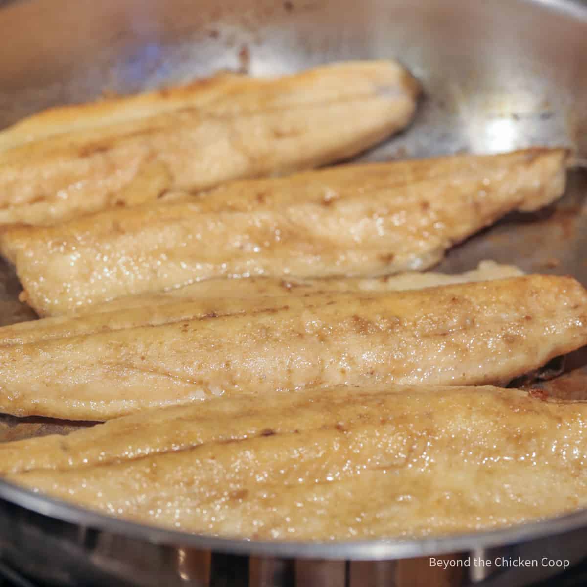 Trout cooking in a pan.