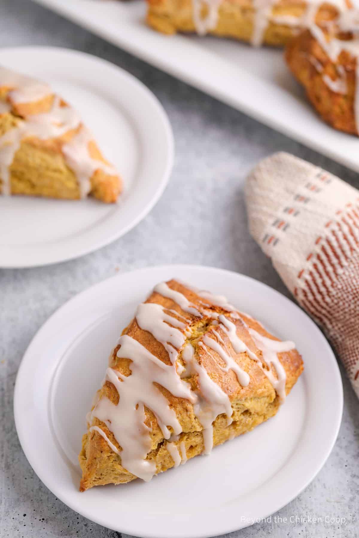 White plates topped with a baked scone with glaze.