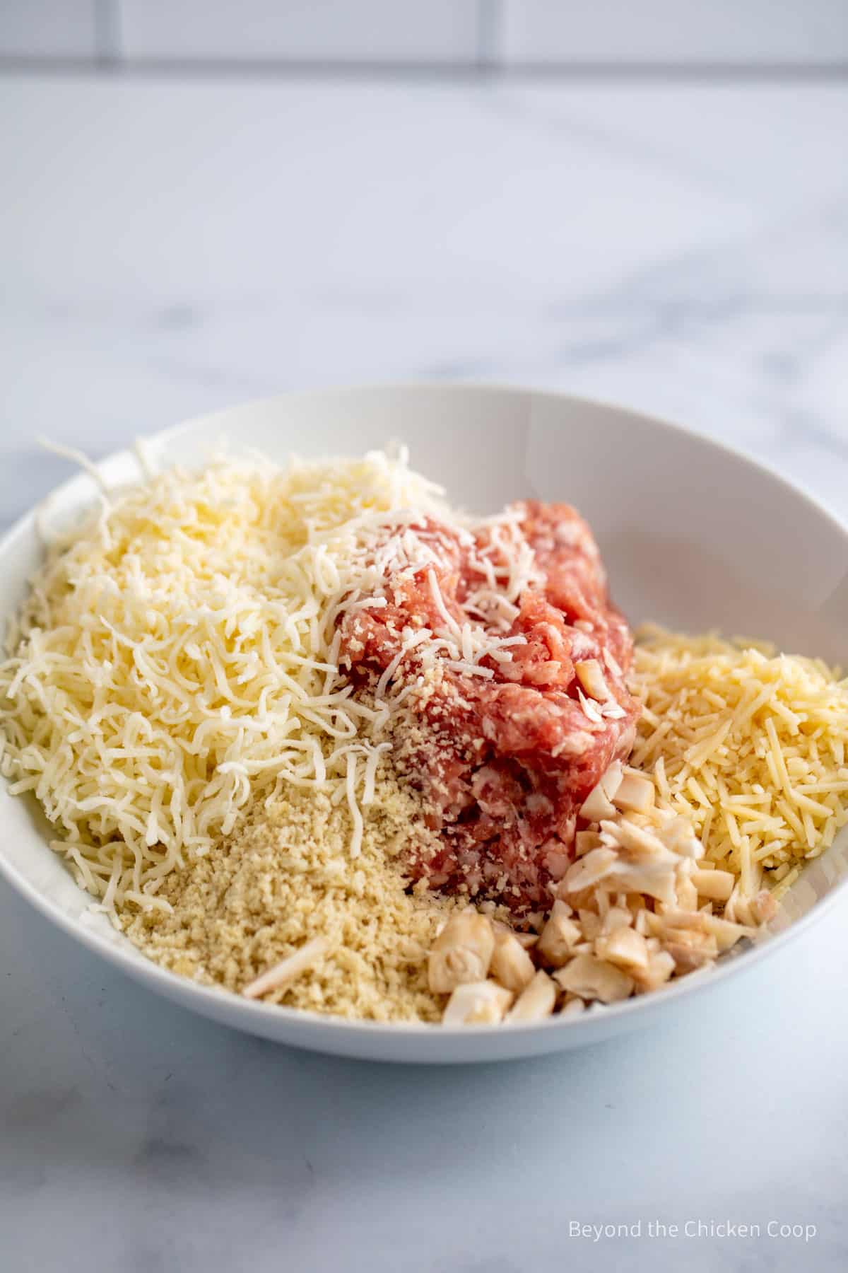 A bowl with sausage, cheese and bread crumbs. 