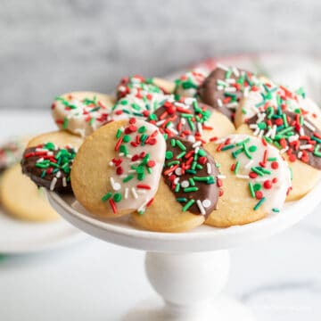 Colorful Christmas cookies on a white cake stand.