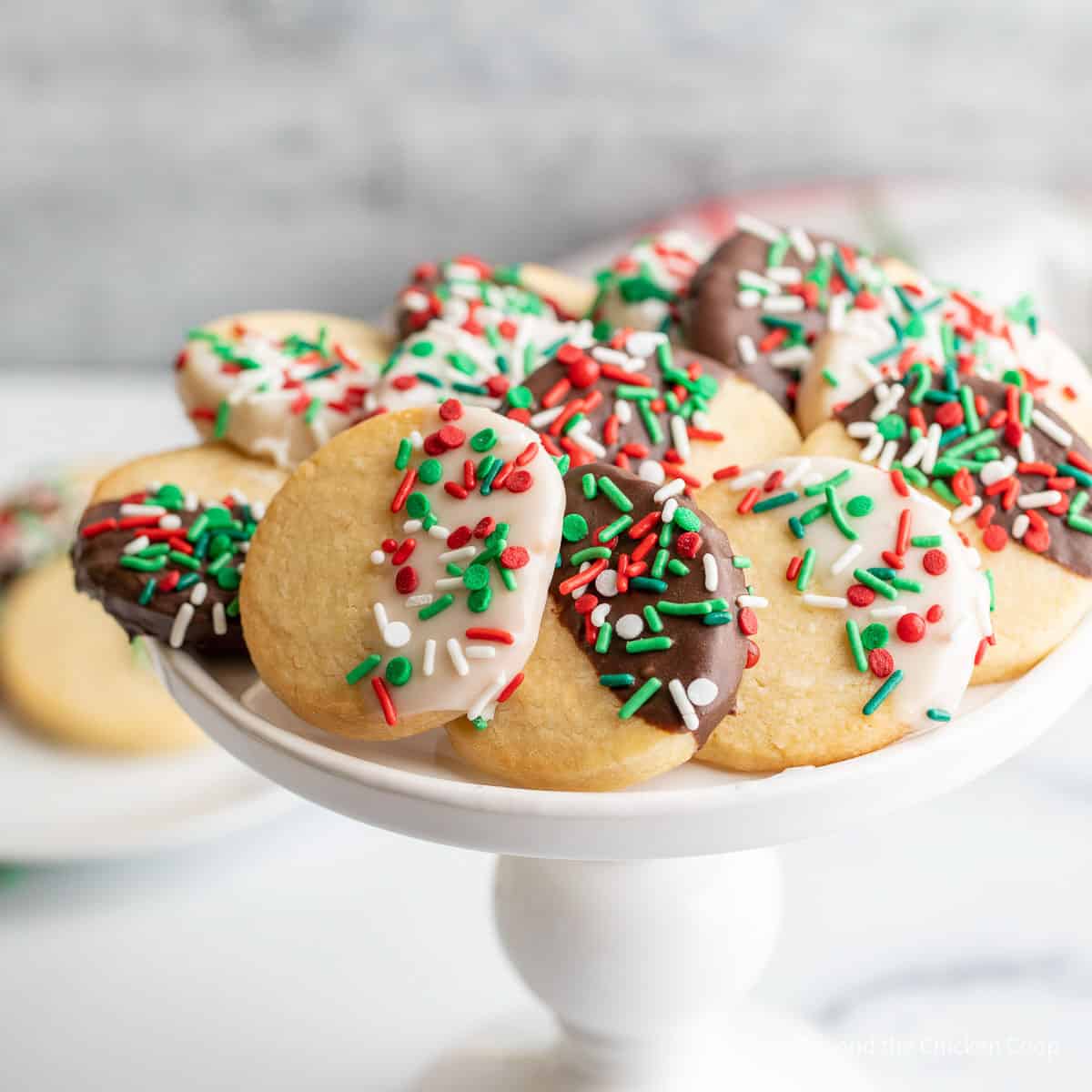 Colorful Christmas cookies on a white cake stand. 