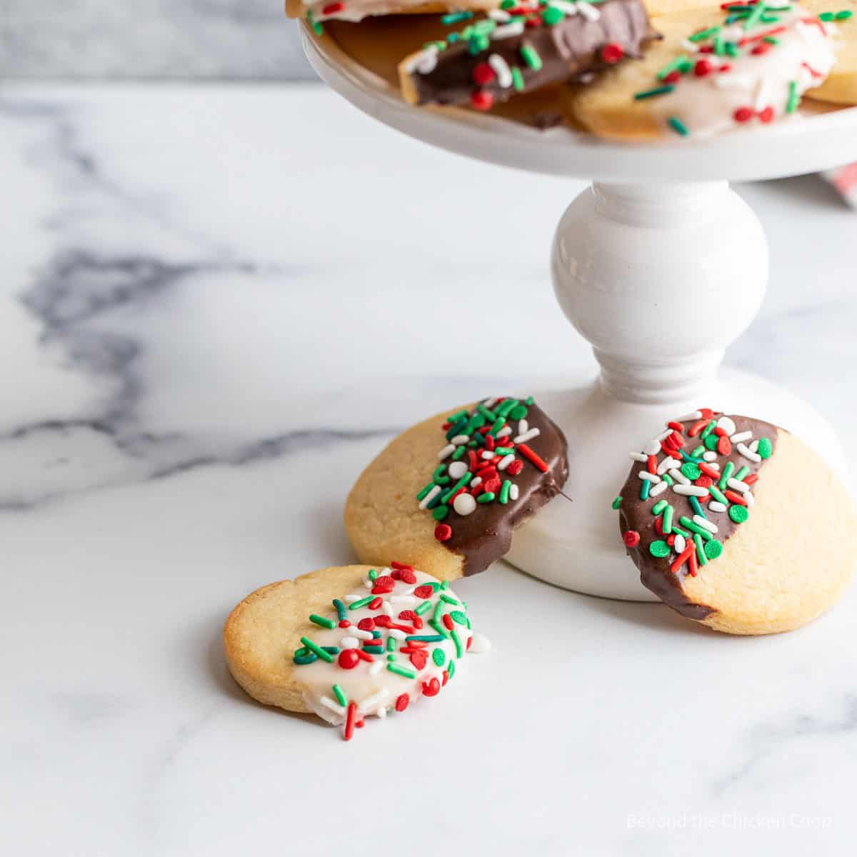 Shortbread cookies with sprinkles near a platter of cookies. 