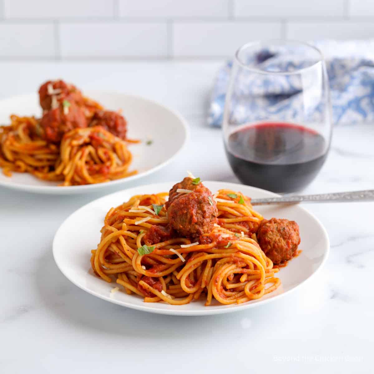 Two plates filled with spaghetti and meatballs. 