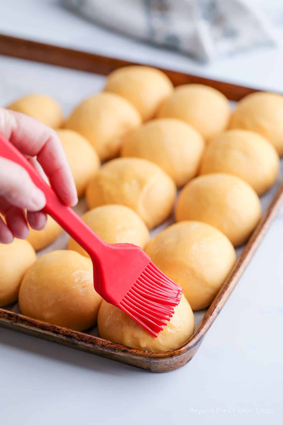 Brushing butter on unbaked rolls. 