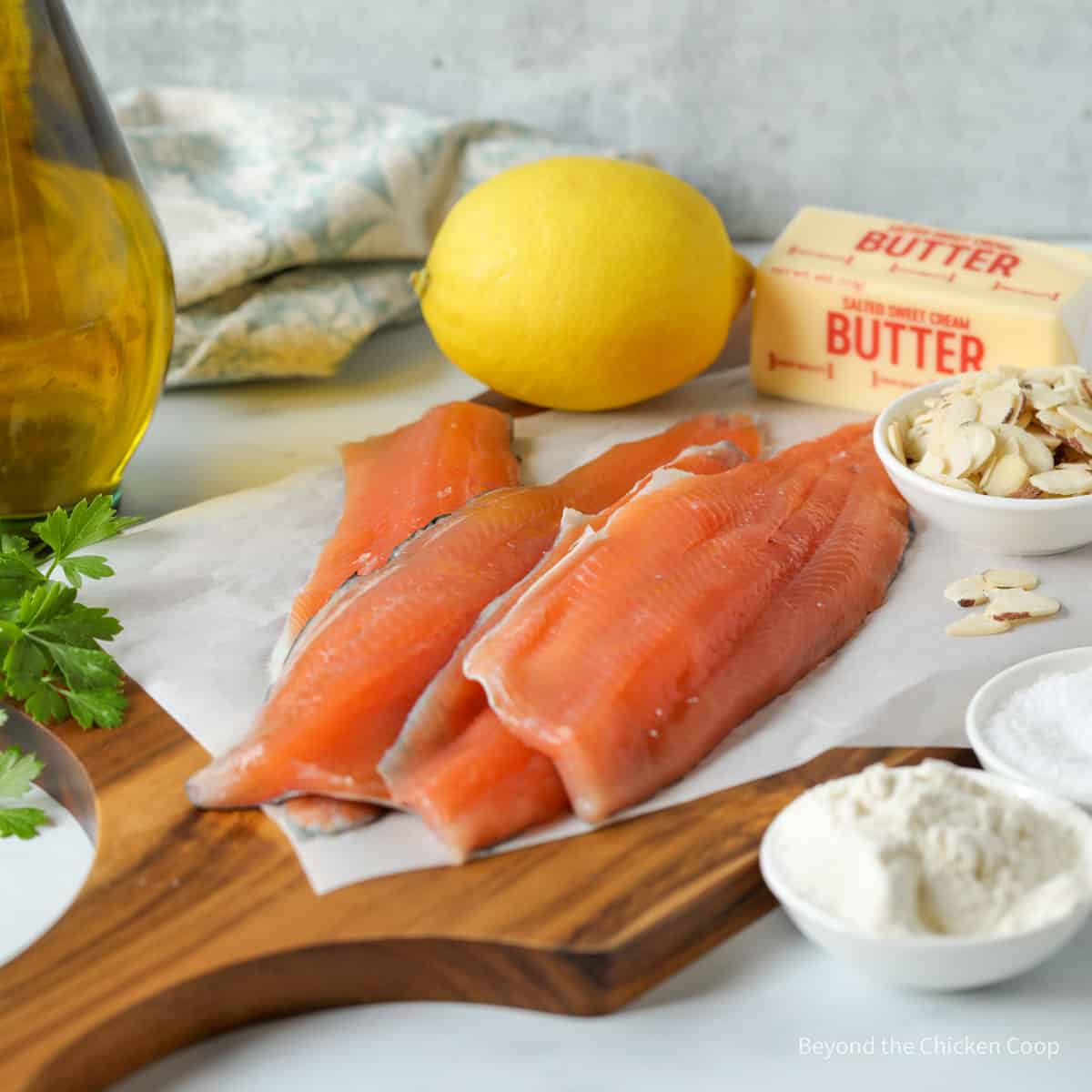 Rainbow trout fillet on a board near butter and a lemon.