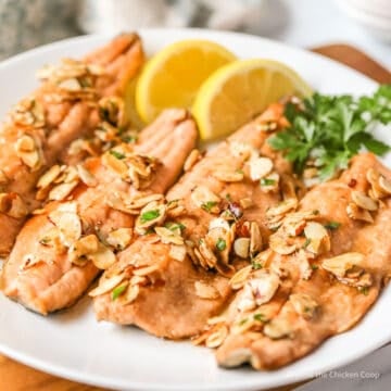 Four fish fillets topped with sliced almonds.