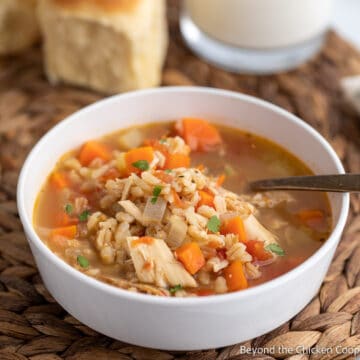A bowl of soup with turkey, carrots and barley.