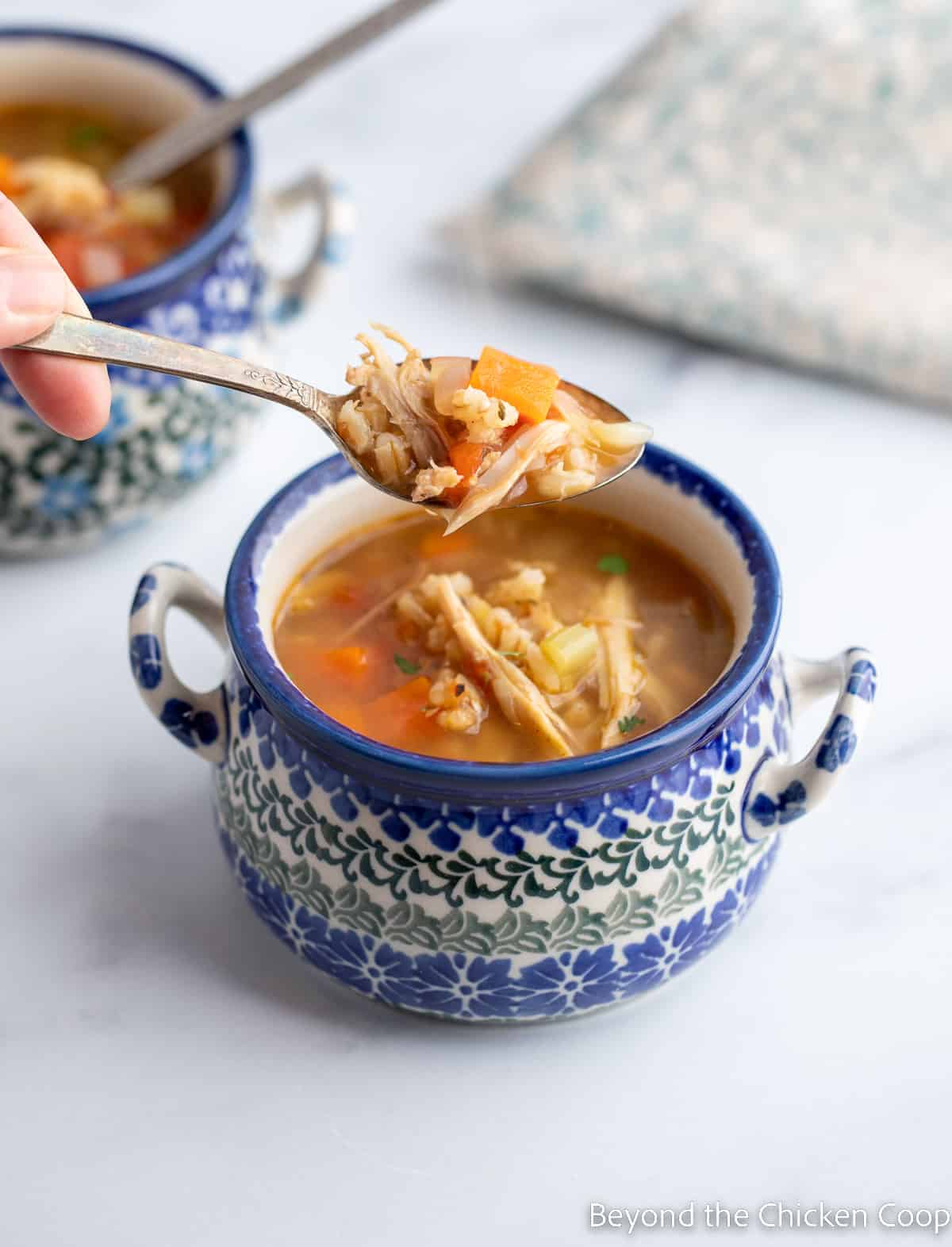 A spoonful of soup over a blue and white bowl.