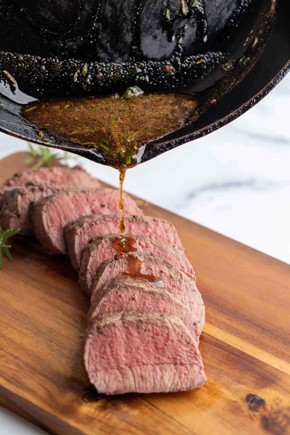 Pouring butter over sliced venison backstrap. 