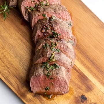 Venison backstrap cut into pieces and fanned out on a cutting board.