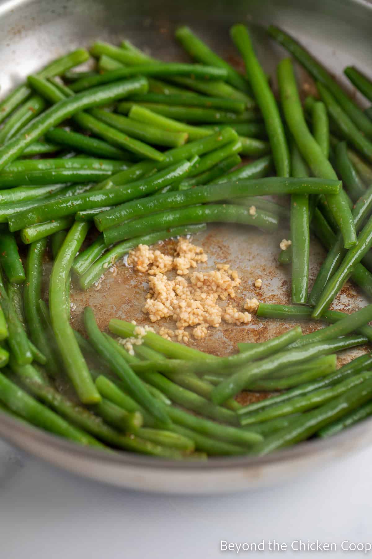 Garlic in the center of a pan with green beans. 