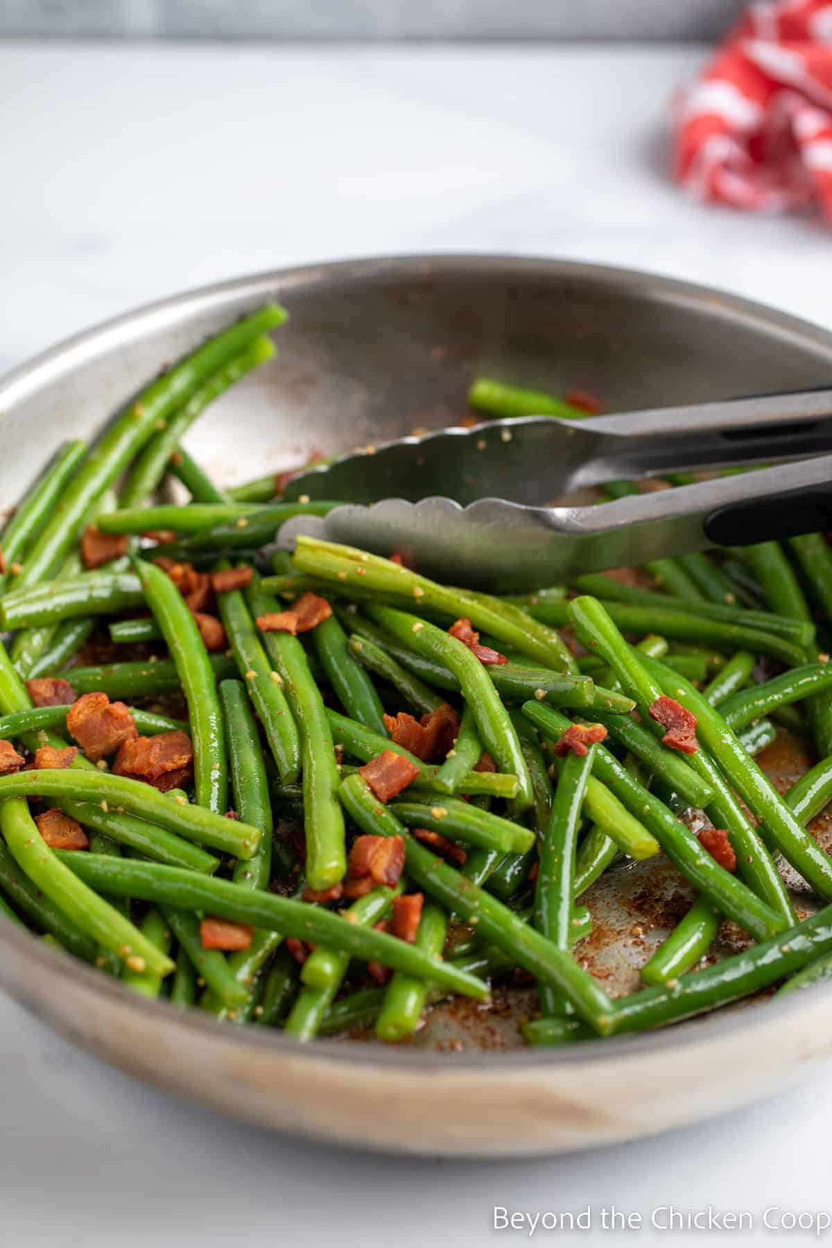 Bacon added to a pan of green beans. 