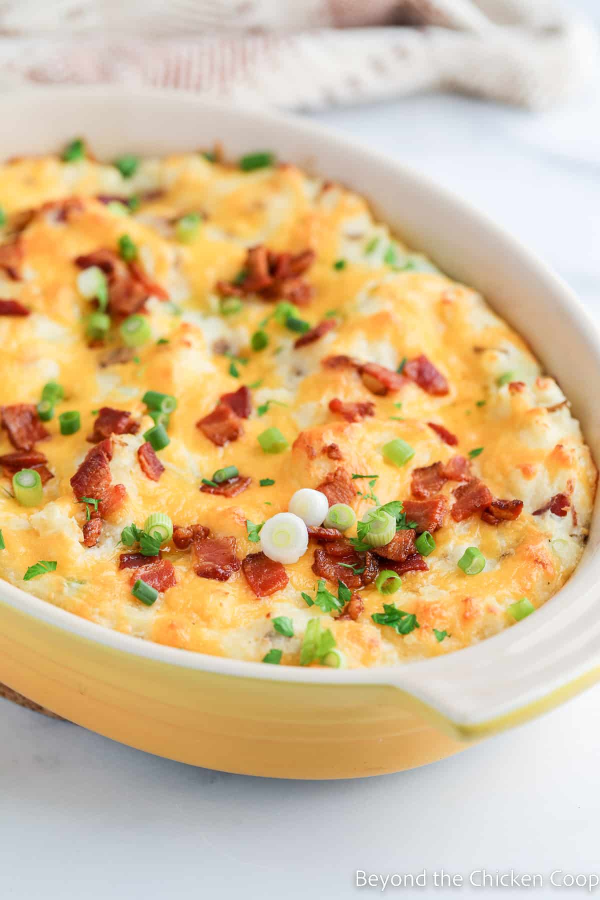 Baked potato casserole topped with bacon and green onions.