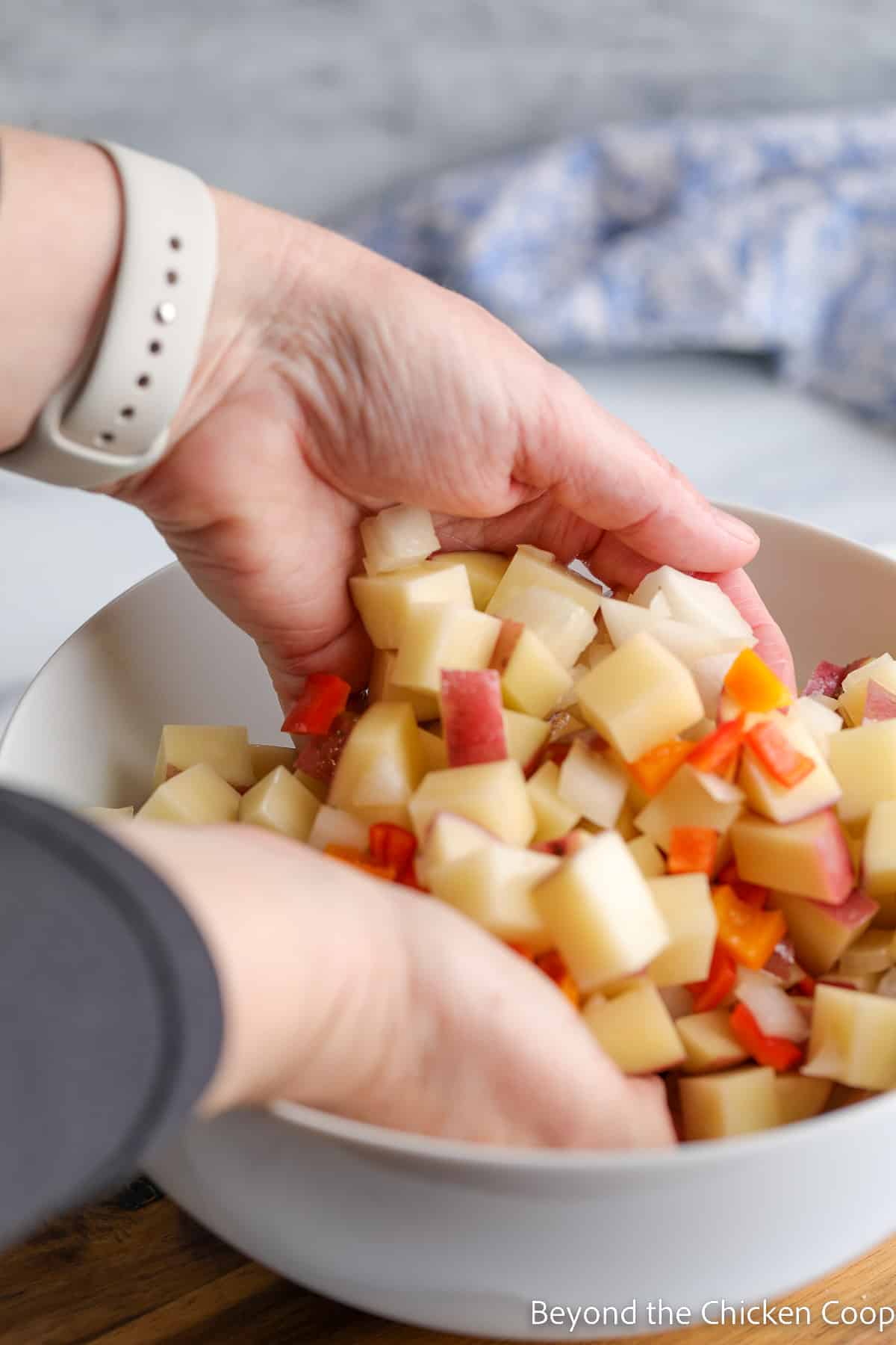 Stirring potatoes in a bowl with hands. 