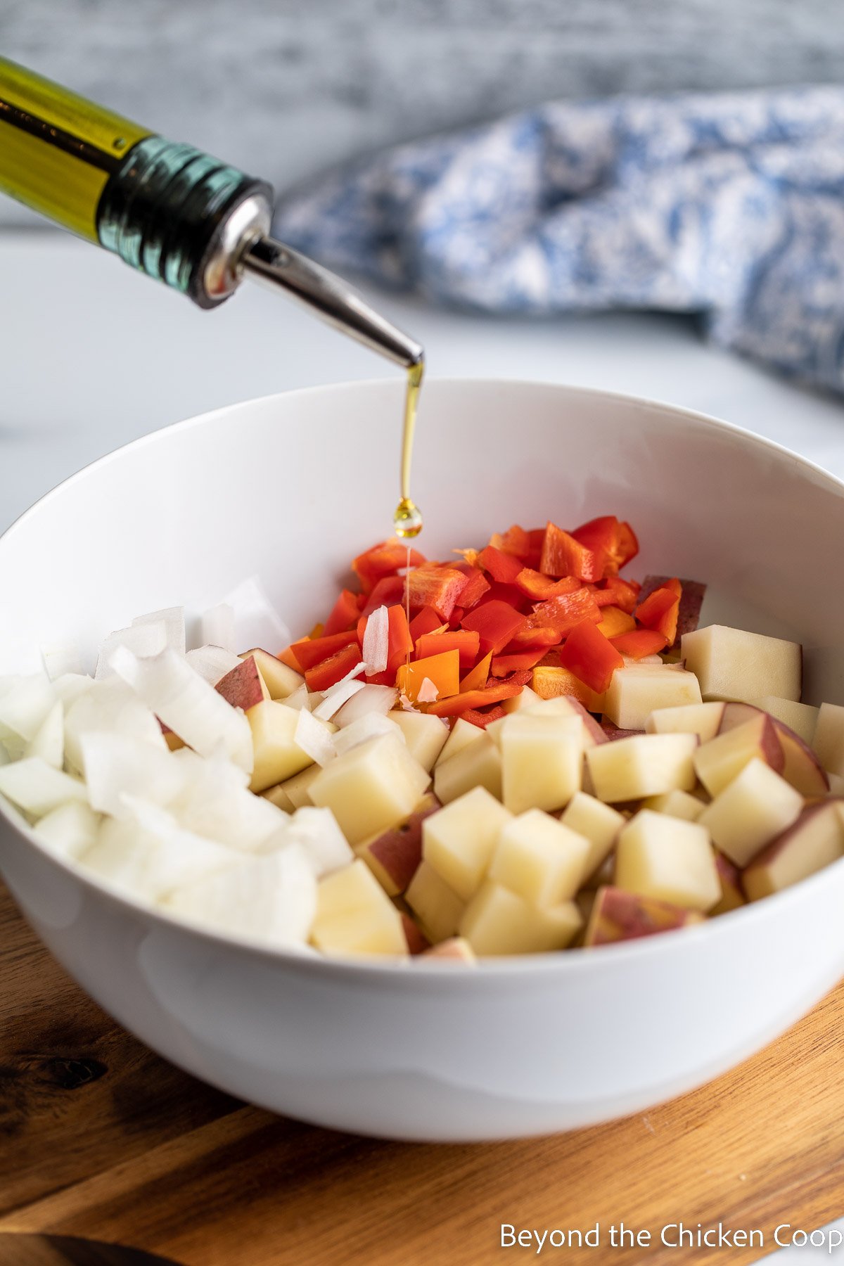 Pouring olive oil over cut potatoes. 