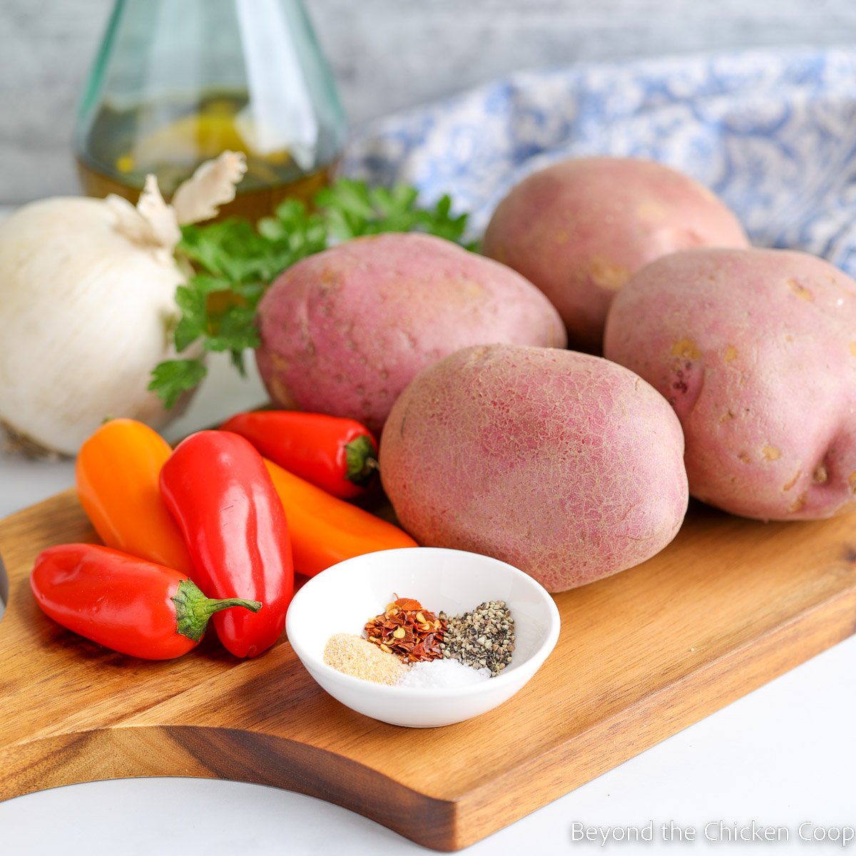 Red potatoes and mini bell peppers on a cutting board.