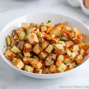 A bowl filled with crispy cubed potatoes.