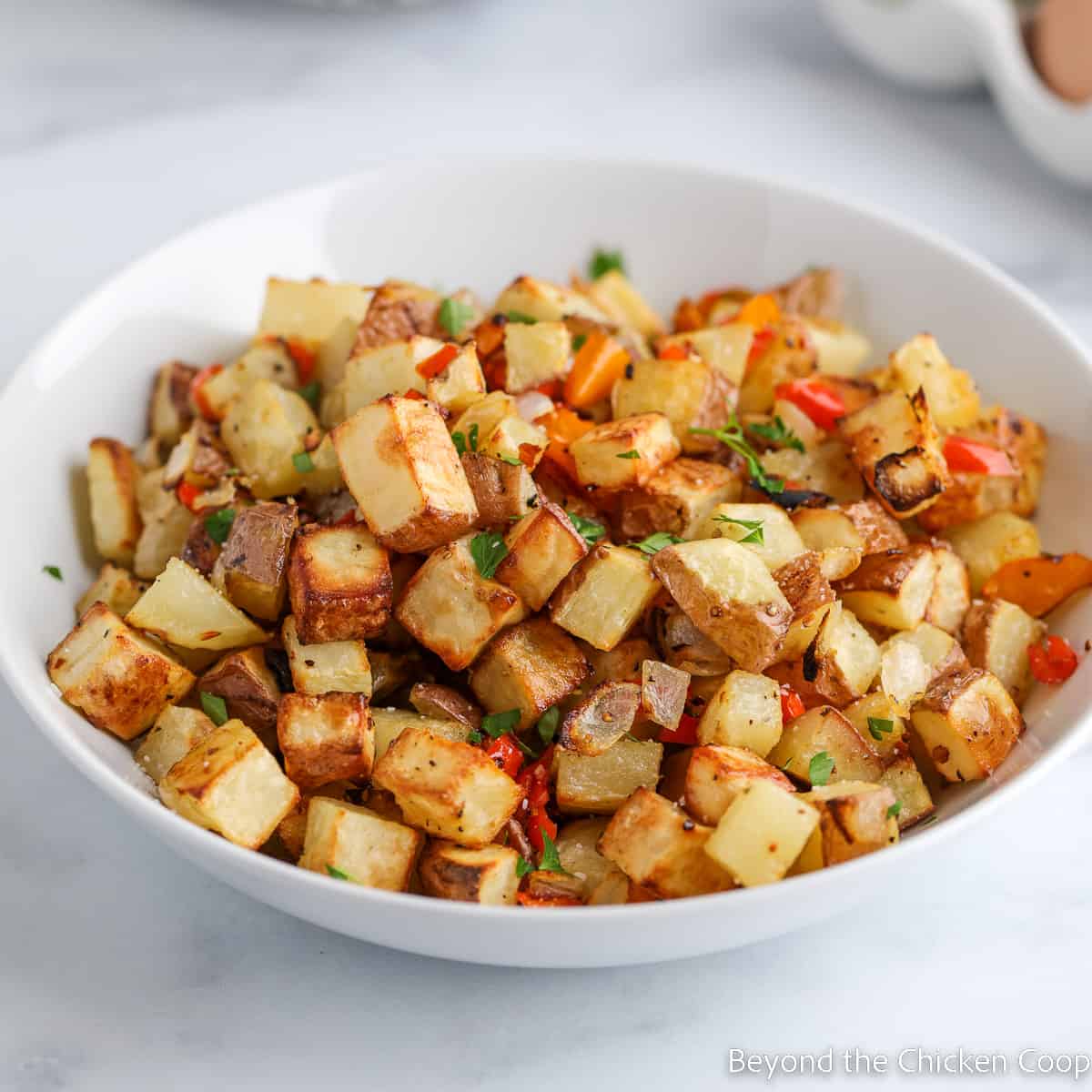 A bowl filled with crispy cubed potatoes.