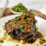 Cooked elk osso buco on a plate with mashed potatoes.