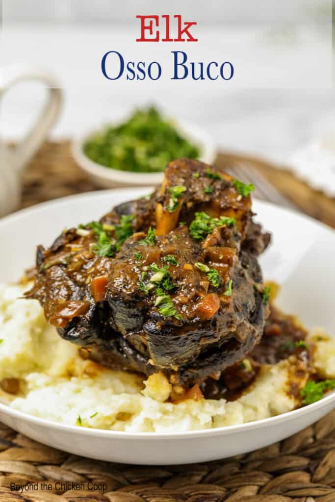 Cooked elk osso buco on a plate with mashed potatoes.