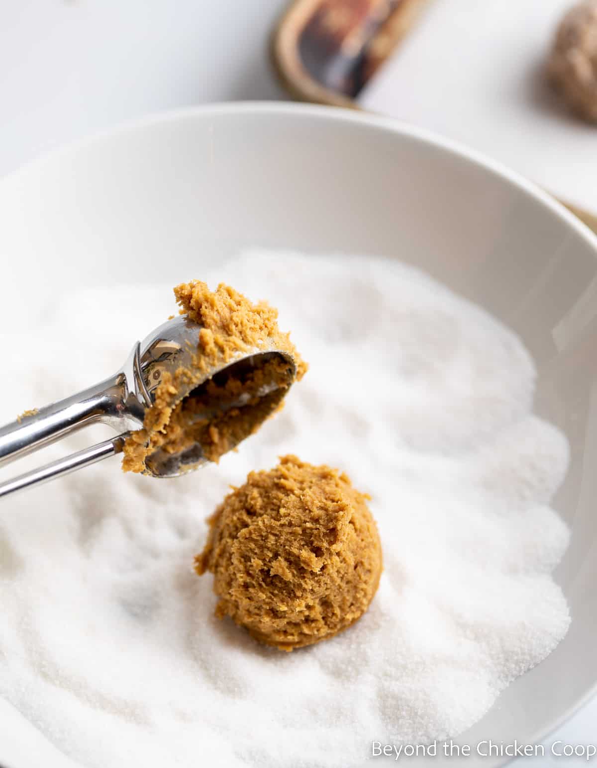 A ball of cookie dough in a bowl of sugar. 